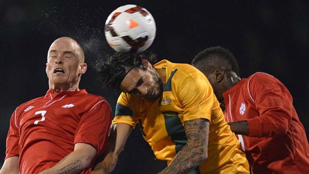 Australia's Rhys Williams (C) rises above Canada's Iain Hume (L) and Tostaint Ricketts (R).