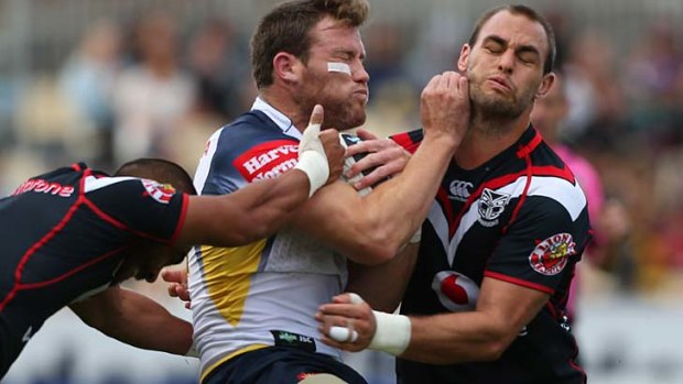 Gavin Cooper of the Cowboys fends Simon Mannering of the Warriors.