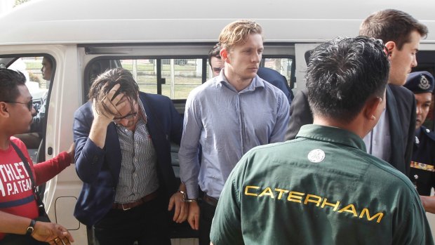 Nick Kelly, second left, and Thomas Whitworth, centre, two of the nine Australian men arrested arrive at the Sepang Magistrate in Sepang on Thursday.