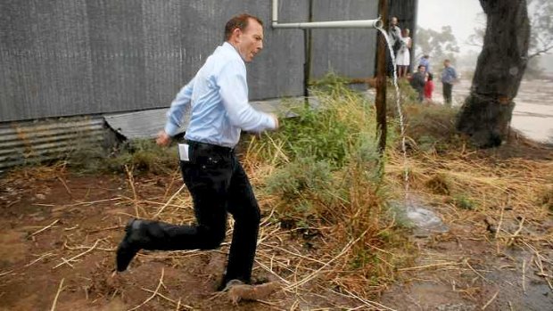 Bringing the rain: Prime Minister Tony Abbott runs for cover during a tour of drought-affected areas that included Bourke in western NSW.