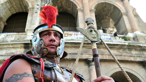 A man as a Roman centurion and who earn his living by posing with tourists gestures in front of the Colosseum during the protest.