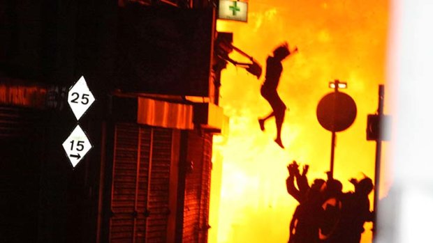 A woman jumps from a building in Croyon, south London which was set alight during riots and looting.