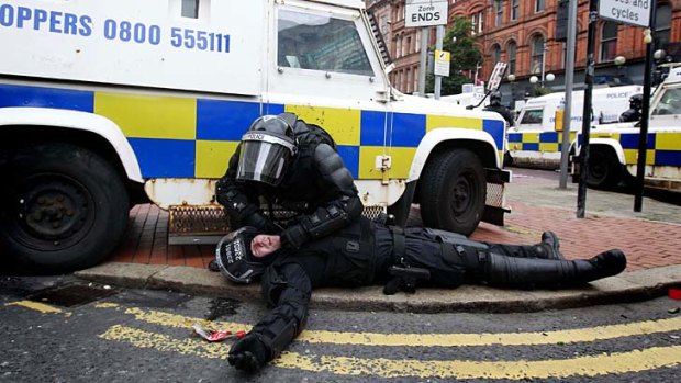 Tensions running high: A policeman lies injured after being attacked by protesters near Belfast city centre.
