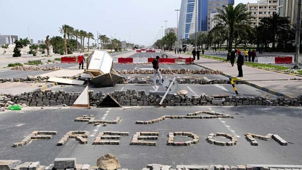 Anti-government protesters stand close to makeshift roadblocks in Manama, the capital of Bahrain, yesterday.