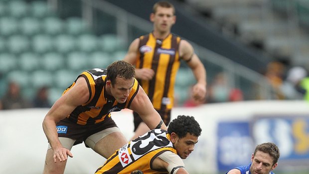 Hawthorn's Cyril Rioli attempts to prise the ball away from Brady Rawlings of the Kangaroos.