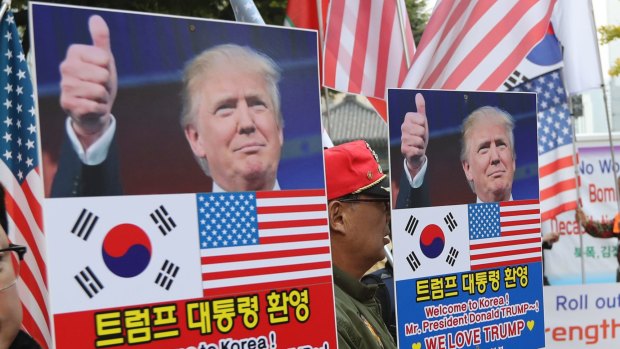 South Koreans hold banners with pictures of US President Donald Trump during a rally ahead of his visit.