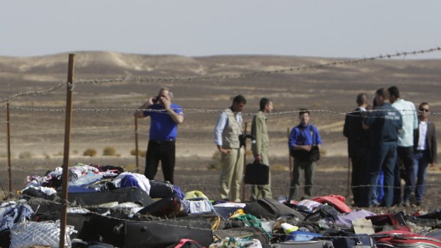 Russian investigators stand near debris, luggage and personal effects at the crash site.