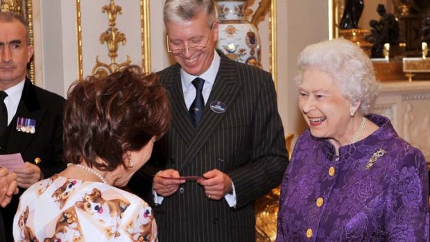All dressed pup ... the Queen shows her appreciation of Kathy Lette's corgi-covered choice of outfit at a reception for Australians living in Britain.
