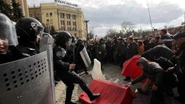 A Ukrainian riot police officer tries to prevent a pro-Russian demonstrator from picking up part of a road block during a rally near the regional administrative building in Kharkiv, Ukraine.