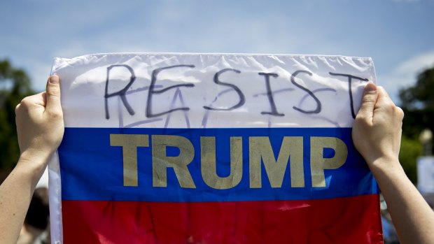 A demonstrator holds a Russian flag displaying the words "Resist Trump" on it during a protest outside the White House.