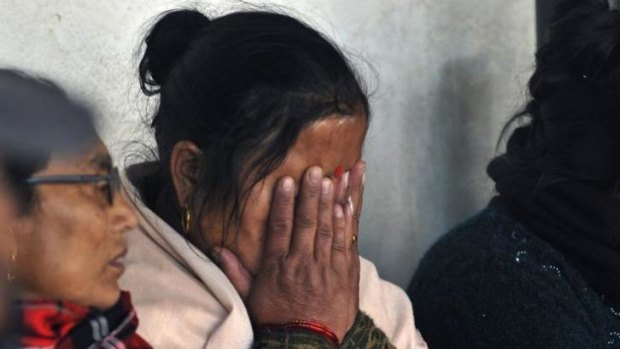 A woman mourns as the victims of a plane crash are taken for a post-mortem at a teaching hospital in Kathmandu.
