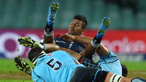 Up and under: Rebel Kurtley Beale is knocked off his feet against his old club in Sydney last night.