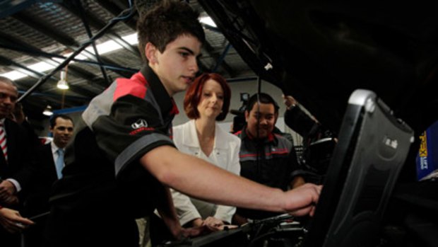 On the tools ... Prime Minister Julia Gillard takes a peek under a bonnet in the workshop of Trivett Honda in Blacktown, guided by  apprentices Nathan Clarke (left) and Terence Manalansan.