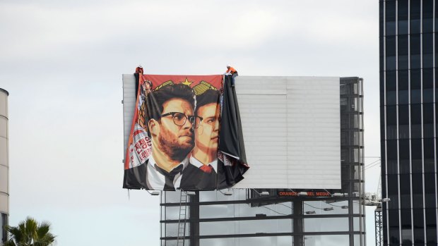 Workers remove a poster for <i>The Interview</i> from a Hollywood billboard.