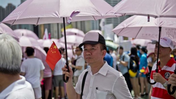 A man holds a Chinese flag and an umbrella at Sunday's pro-government rally in Hong Kong.