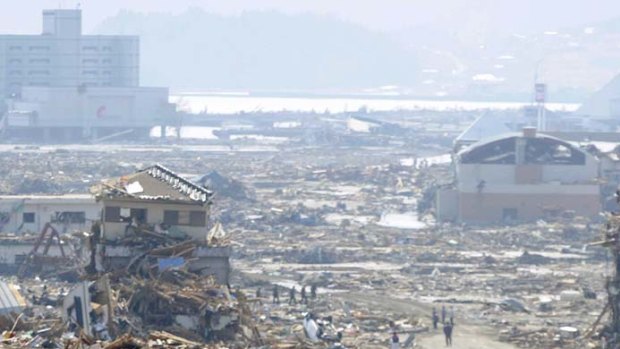 People walk amid the rubble in Rikuzentakata, Iwate prefecture.