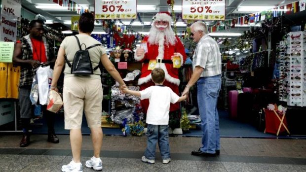Shoppers stop to inspect a Santa Claus figure.