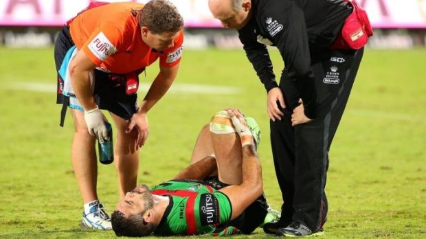Greg Inglis clutches at his leg while being treated by Rabbitohs medicos in Perth.