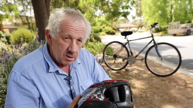 Brian Pearce, 60, shows his split helmet and damaged bicycle outside his Tuggeranong home. 