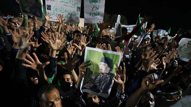 Not drowning, waving ... supporters of Muammar Gaddafi chant and display pictures of their leader during a pro-government rally in Tripoli on Thursday.