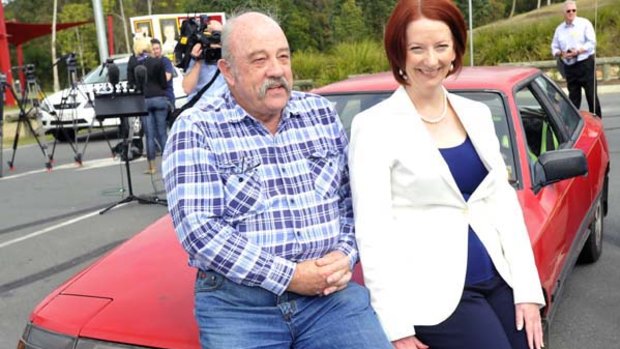 Prime Minister Julia Gillard sits on the boonet of a 1987 Celica with owner Colin Foot at Beenleigh south of Brisbane at the weekend as she announced her 'cash for clunkers' policy.