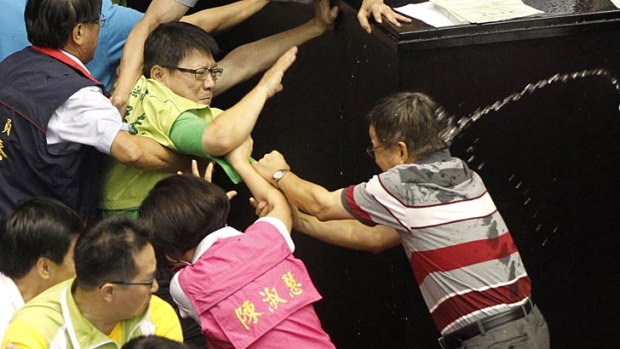 Ruling and opposition lawmakers are sprayed with water as they fight on the legislature floor in Taipei.