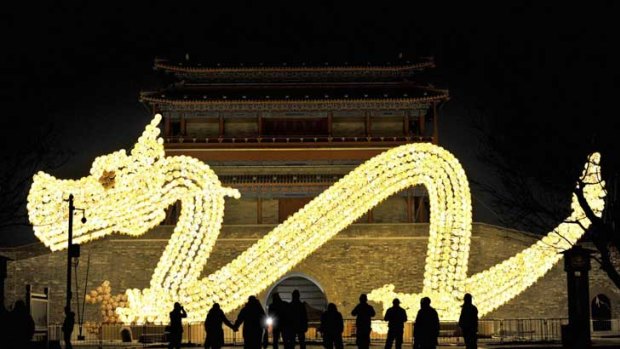 Visitors take pictures in front of a dragon-shaped lantern which has been set up for the upcoming Lunar New Year in Beijing.