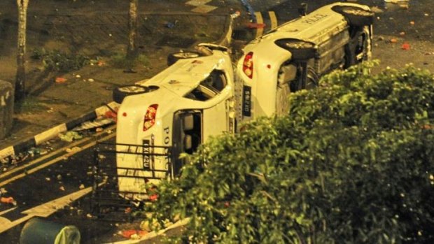 Two police cars flipped on their sides remain in the street after a riot broke out in Singapore.