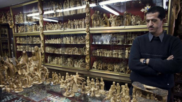 A Palestinian sells olive wood nativity scenes in his shop in Bethlehem.
