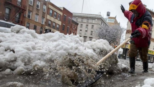 A worker clears snow and ice in Brooklyn, New York.