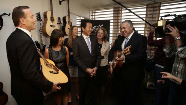 Striking a chord: Tony Abbott, his daughter Frances, third from left, and Joe Hockey at a Melbourne guitar factory on Friday.
