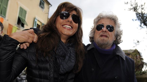 Five Star Movement leader and comedian Beppe Grillo and his wife Parvin Tadjik walk after casting their votes at the polling station in Genoa February 23, 2013.