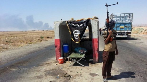 A militant of the Islamic State in Iraq and the Levant (ISIL) stands guard at a checkpoint captured from the Iraqi army outside the Baiji oil refinery.