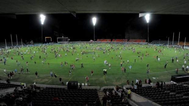 Patrons on the field after an AFL NAB Cup match between the GWS Giants and Essendon Bombers at Manuka Oval under lights.