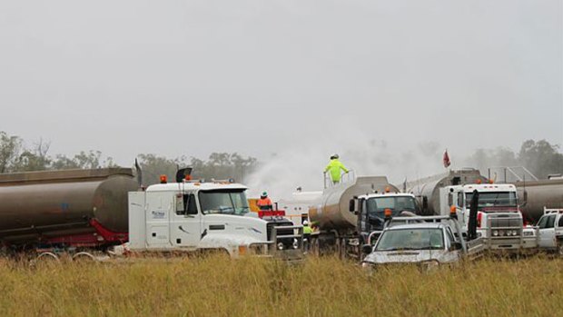 Workers try to stem the leak of water and gas from a well near Dalby this morning.