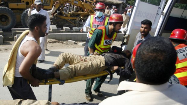 Pakistani police and ambulance officers carry the injured to safety during the attack.