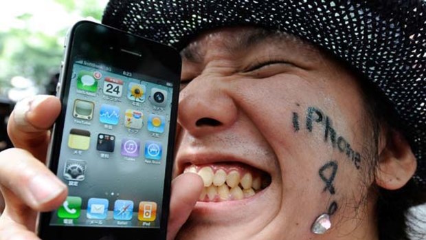 A jubilant Japanese iPhone 4 buyer celebrates his new purchase. Australian Apple fans will get their turn with the company's latest glamour product from tomorrow.