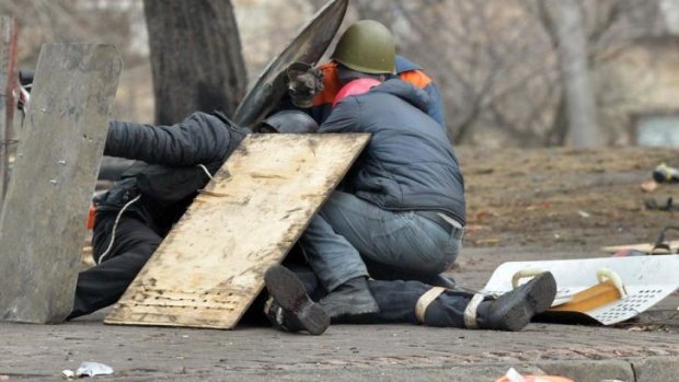 Pro-European Maidan self-defence activists covering a killed protester with shields in Institutskaya Street in Kiev in February.  