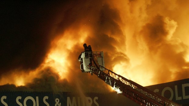 A firefighter tries to extinguish a raging fire of a carpet warehouse in the Paris suburb, Aulnay-sous-Bois, in 2005. 