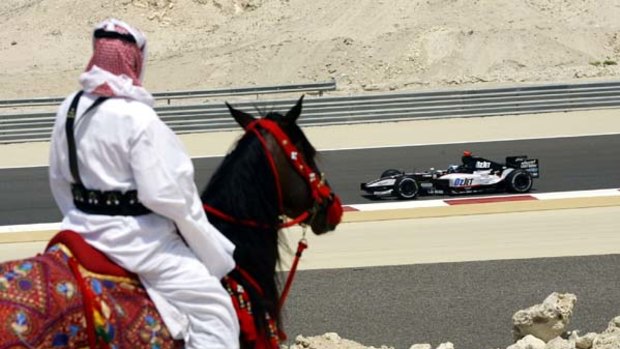 Abdel Rouf, a member of the Bahrainian Royal Arab Studs, watches Minardi's driver Patrick Friesacher of Austria at the Bahrain International Circuit in  2005.