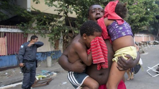 A man runs while he carries two children during an eviction in Rio.