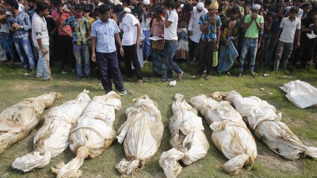 Bodies of unidentified garment workers, who died in the collapse of the Rana Plaza building in Savar, lie on the ground as people gather to watch a mass burial in Dhaka on Wednesday.