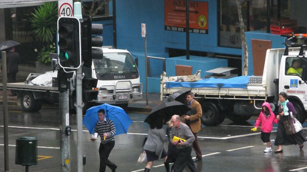 Pedestrians battle the wet weather in Brisbane's CBD this morning.