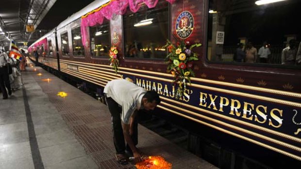 Goodbye and good luck ... a railway worker lights an earthenware candle in preparation for the departure of the Maharajas' Express.