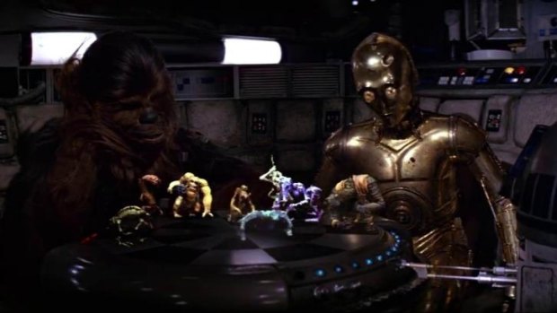 Chewbacca (Peter Mayhew) playing R2-D2 (Kenny Baker) in a holographic chess game, while C3-PO (Anthony Daniels) looks on, in a scene from the 1977 film Star Wars.