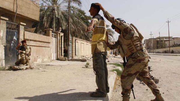 An Iraqi soldier frisks a resident in Basra.