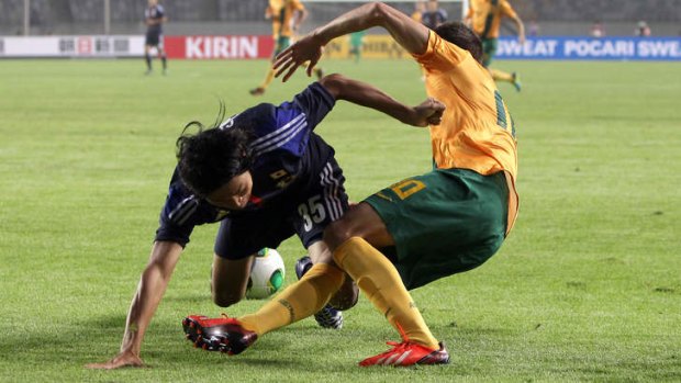 Dario Vidosic of Australia and Kazuhiko Chiba of Japan fall over each other in contest for the ball.