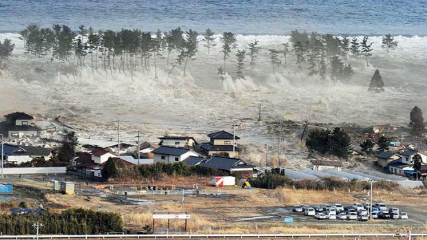 Waves from a tsunami hit residences after a powerful earthquake in Natori, Miyagi prefecture.