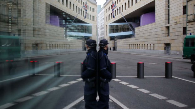 The British Embassy in Germany and a guarding police officer are reflected in the window of a building in Berlin.