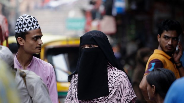 An Indian Muslim woman walks at a market area in Delhi, India.